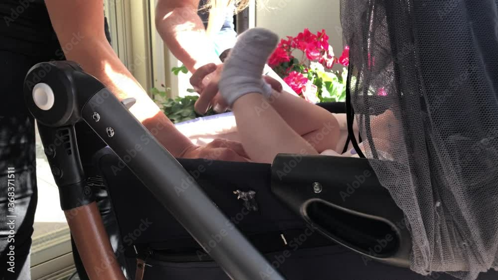 Mother is cleaning a baby bum and changing a baby's diaper in a stroller.