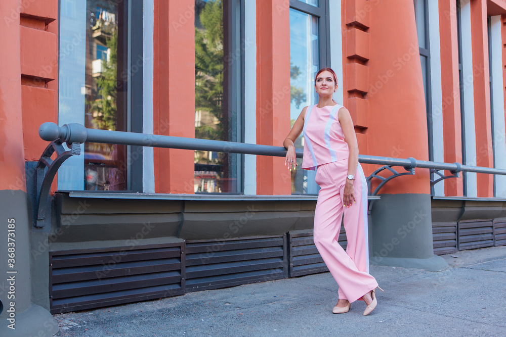 Young woman wearing pink suit posing on the street next to the old building Young woman wearing pink suit posing on the street next to the old building