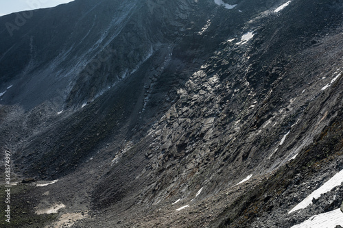 The concept of outdoor activities in the mountains. Minimalist mountain landscape with a snowy field on the pass, with snow on the side of the mountain.