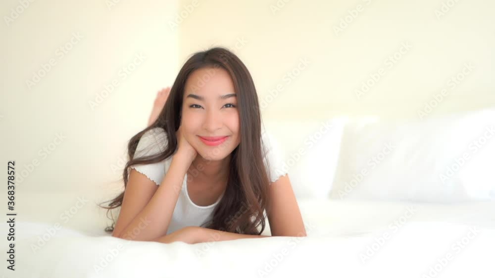 Slow pan of an attractive young woman lying on her stomach a big comfy bed. Slow pan of an attractive young woman lying on her stomach a big comfy bed.