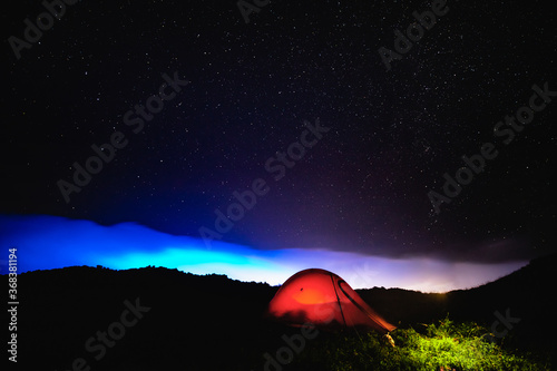Under the beautiful starry sky, the top of the mountain is dazzled and dazzled. The orange tent under the Milky way at night.