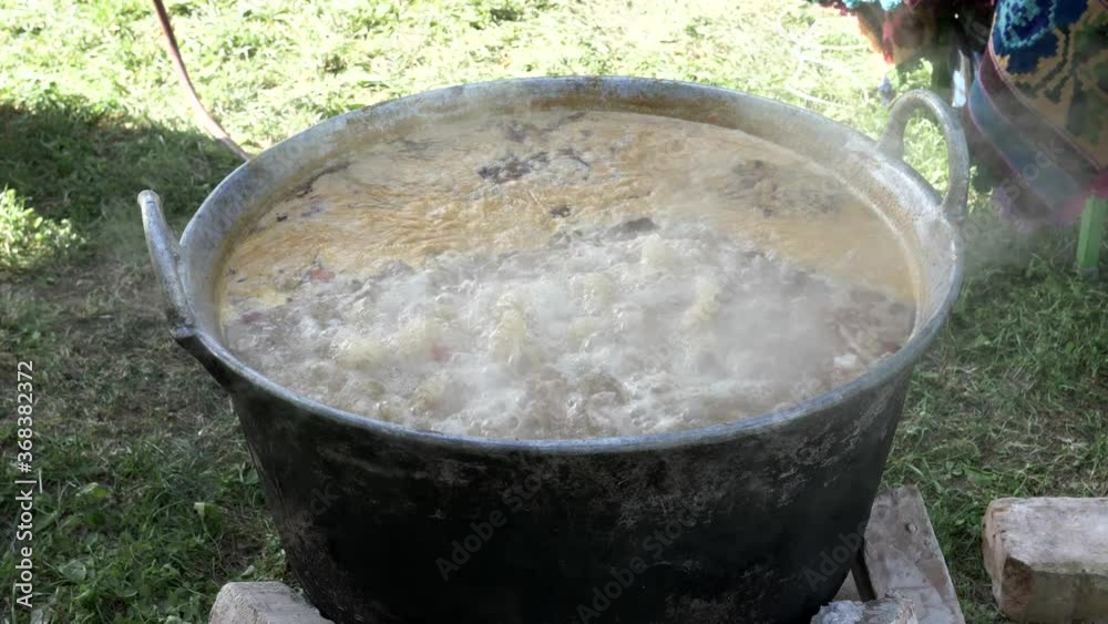 Cooking traditional soup in a large cauldron, on a open air -slow motion. Cooking traditional soup in a large cauldron, on a open air -slow motion.