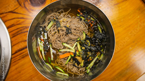 Top view of Korean summer speciality food, cold buckwheat soba noodles,memil guksu, on a stainless steel bowl photo