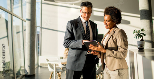 Foto Multiethnic business people using digital tablet while standing in the office