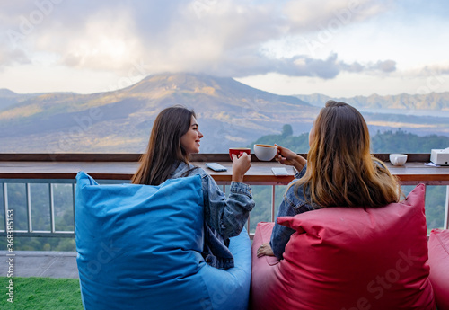 girlfriends sit and drink coffee on the background of the volcano.
