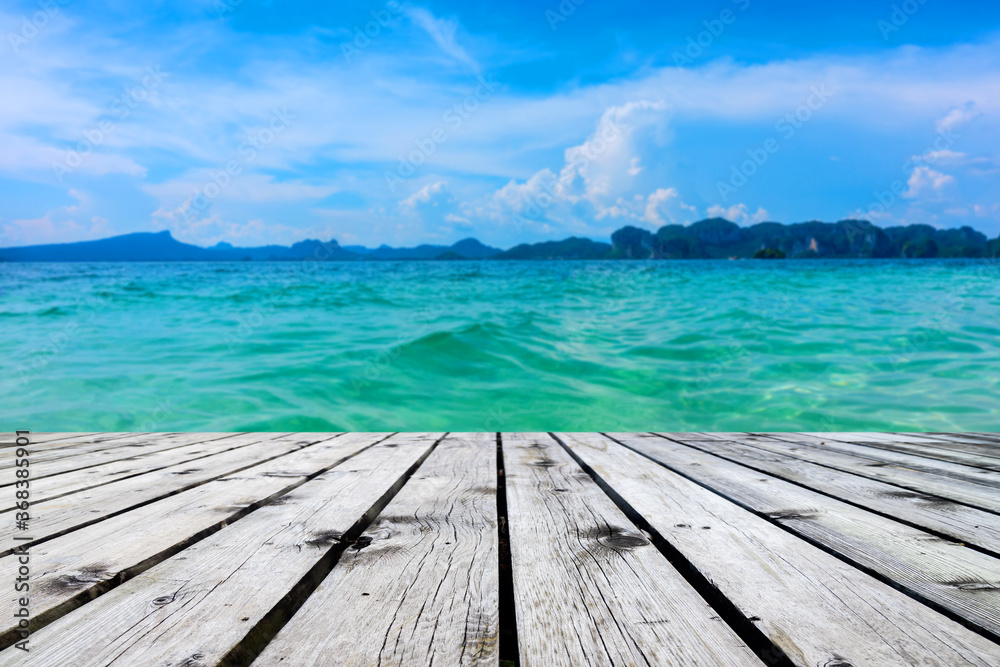 Fototapeta premium Wooden floor or plank on sand beach in summer. For product display.Calm Sea and Blue Sky Background.