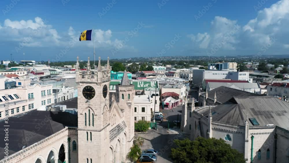Drone moves over the roofs of houses from Barbados Parliament building with barbadian flag in Bridgetown