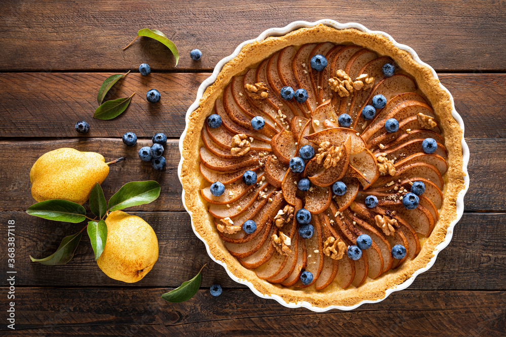 Fototapeta premium Thanksgiving pear tart, pie or cake with fresh pears and blueberry, cinnamon and walnuts