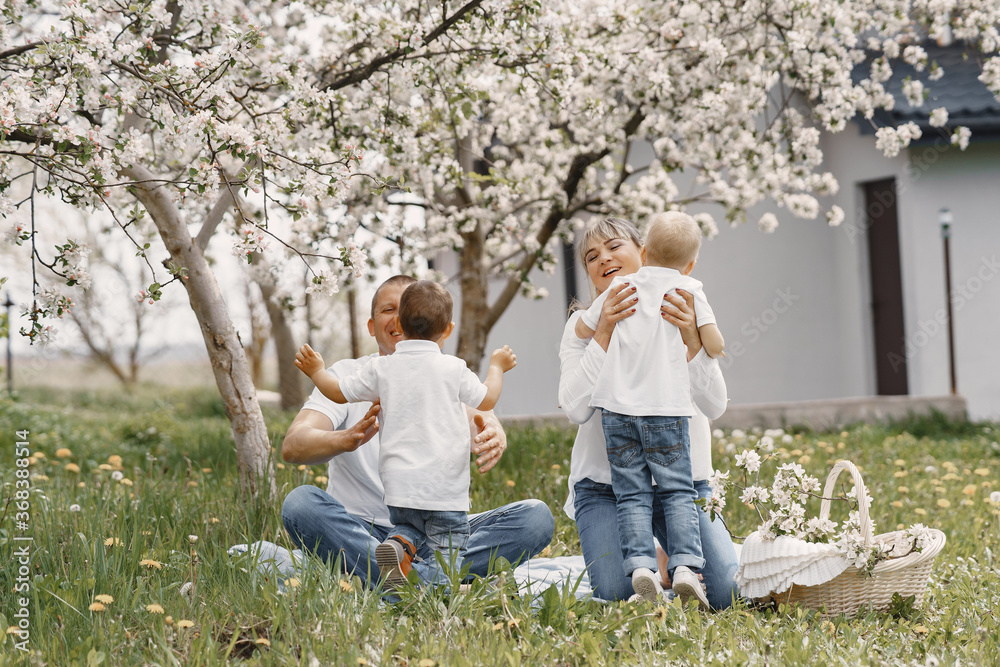 Fototapeta premium Family with cute little children. Father in a white shirt. People have a picnic on a yard.