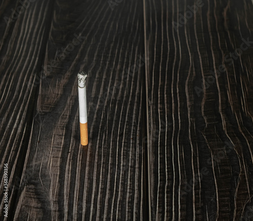 burning cigarette in a wooden background. narcotic concept.