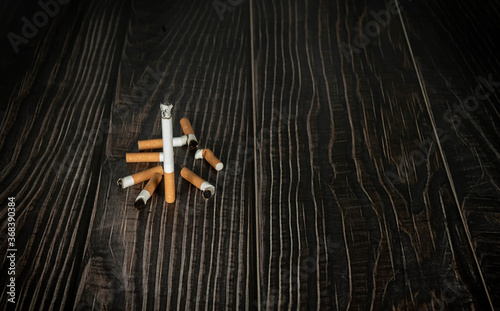 a burning cigarette and cigarette butts on a wooden table. narcotic concept.