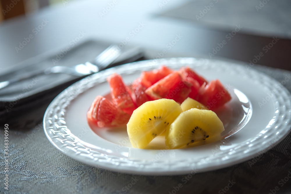 Fruits on white plate. Gold kiwi fruit, blurred pink grapefruit. Healthy life style Fruits on white plate. Gold kiwi fruit, blurred pink grapefruit. Healthy life style