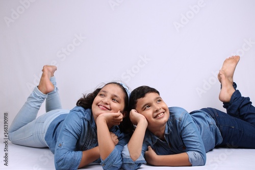 Two cute Indian kids lying over white background.