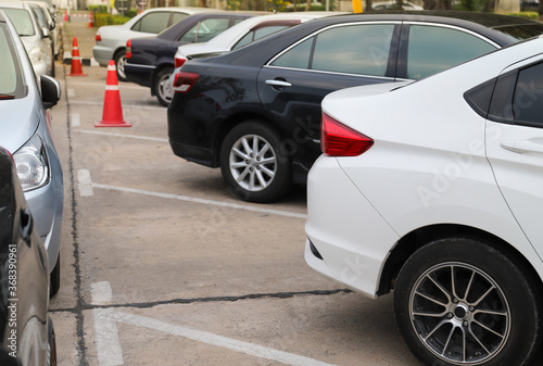 Closeup of rear, back side of white car with other cars parking in outdoor parking area.