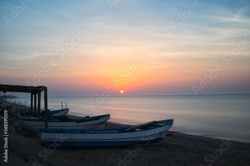 Muscat, Oman. Circa June 2020. A beautiful sunset along a calm beach lined with fishermen's boats.
