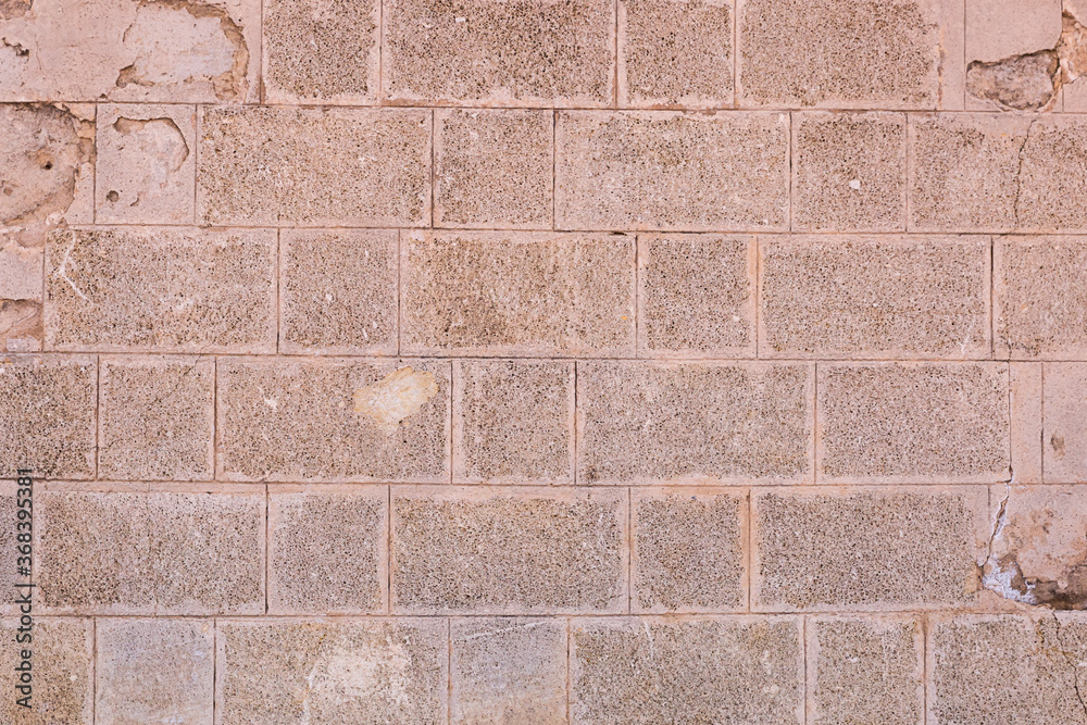 Fototapeta premium stone wall made of rectangular cobblestones background light brown solid weathered