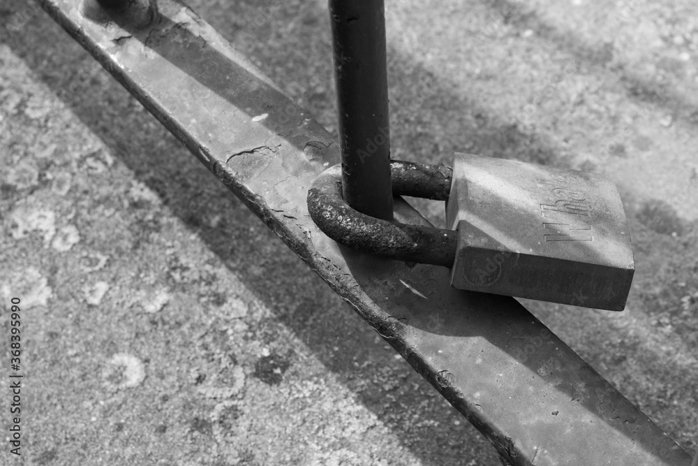 evocative black and white image of a padlock tied to a rusty pole evocative black and white image of a padlock tied to a rusty pole