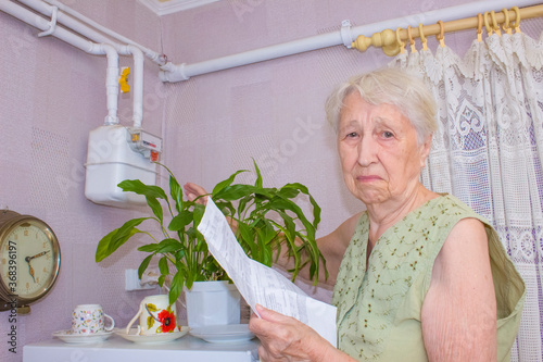 The senior woman at home and examines gas bill