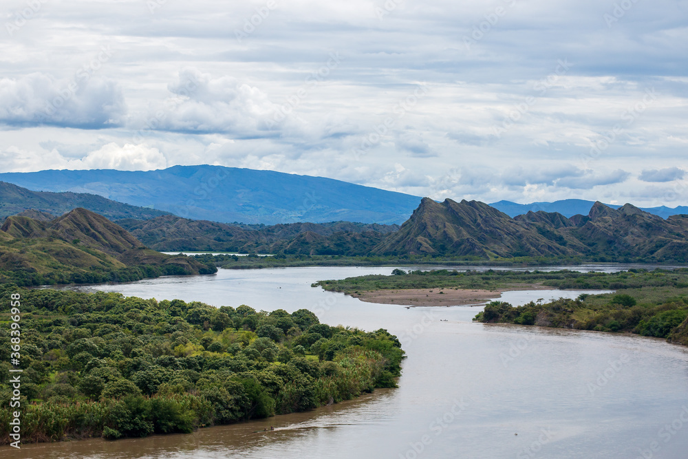 panorama photo of magdalena river in colombia. Big brown river with mountains at the background