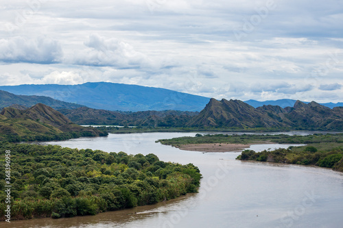 panorama photo of magdalena river in colombia. Big brown river with mountains at the background