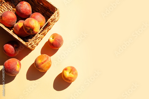 Peaches in a wicker basket on a gentle peach background. Contrast shadows