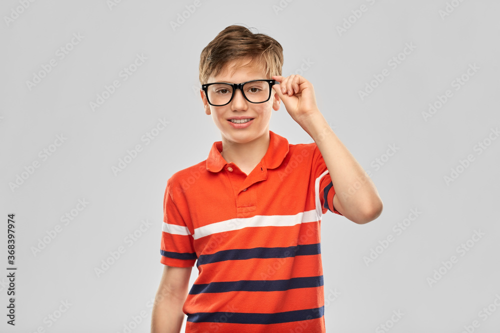 vision, education and school concept - portrait of happy smiling boy in eyeglasses and red polo t-shirt over grey background vision, education and school concept - portrait of happy smiling boy in eyeglasses and red polo t-shirt over grey background