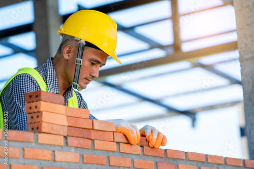 Obraz na płótnie Construction Worker installing bricks on construction site.