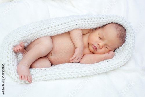 The newborn sleeps peacefully in a knitted cocoon