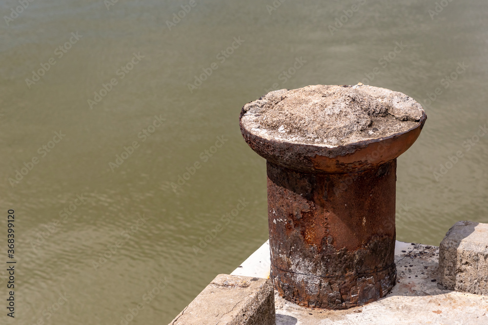 old rusty metal bollard mooring boats on the background of a muddy river old rusty metal bollard mooring boats on the background of a muddy river