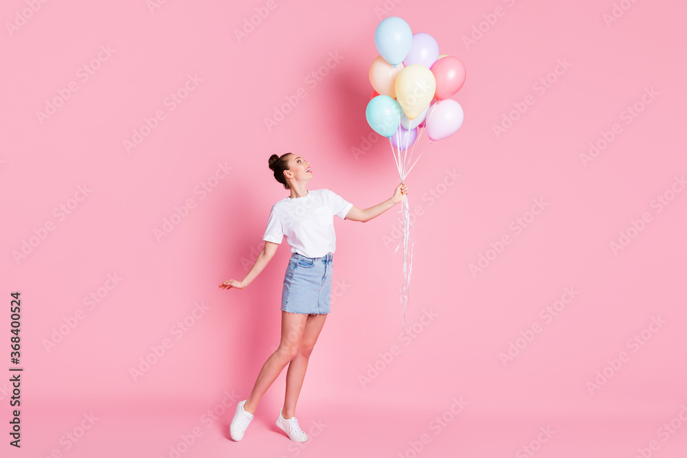 Full length photo of attractive pretty lady pretty bun summer vacation good mood hold many air balloons celebration wear white t-shirt mini skirt shoes isolated pink color background