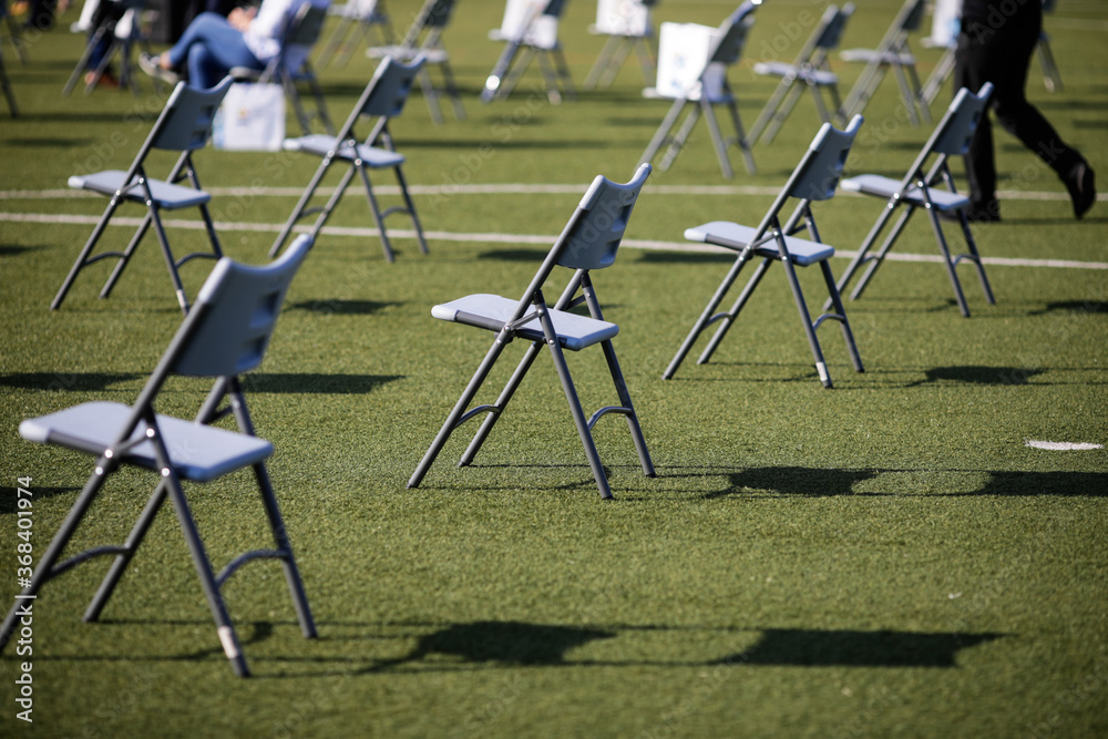 Chairs apart one from another to maintain the social distance during the Covid-19 outbreak at an outdoor event on the turf of a stadium. Chairs apart one from another to maintain the social distance during the Covid-19 outbreak at an outdoor event on the turf of a stadium.