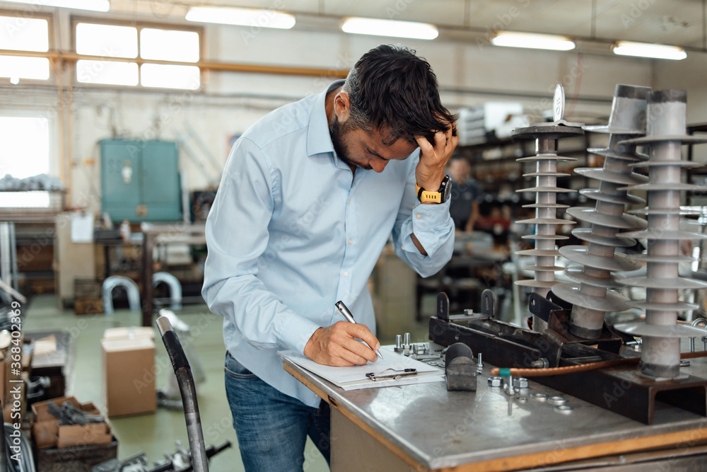 Middle age businessman doing quality control checking at industry production. Factory for industrial production of electric housings and surge arresters. Middle age businessman doing quality control checking at industry production. Factory for industrial production of electric housings and surge arresters.