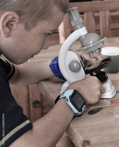  boy with a smart watch on his hand looking through a microscope

