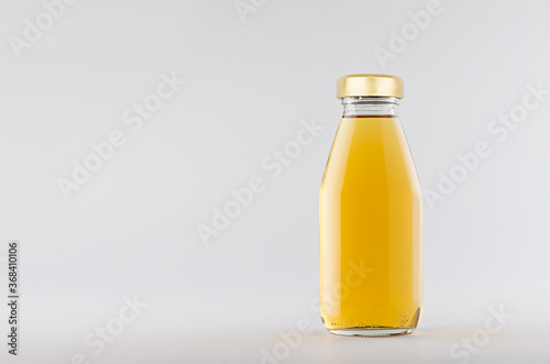 Yellow apple juice in glass bottle with gold cap  mock up on white background with copy space, template for packaging, advertising, design product, branding.