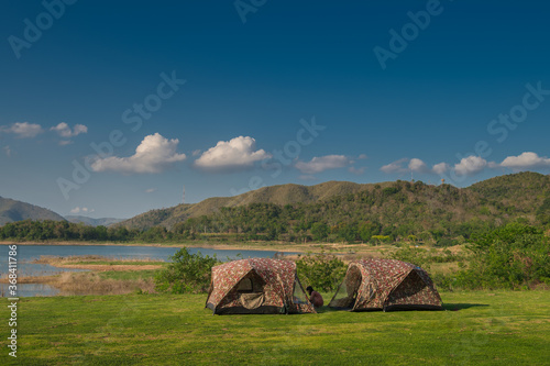 Camp in the mountains near of the lake in Kaeng Krachan Dam in Thailand. Woman  enjoying camping holiday in countryside. Lifestyle and freedom concept.