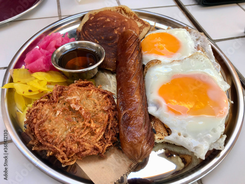 American Breakfast with Pancake Maple Syrup, Sunny Side Up Eggs, Hash Brown, Sausage, Turmeric Pickled Onions and Pickle.