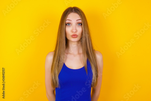 Attractive light haired female rounds lips, wears casual clothes, looks directly into camera, expresses her satisfaction, isolated over gray background. People, body language concept.