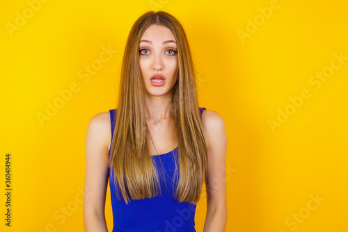 Emotional attractive female with opened mouth expresses great surprisment and frighteness, poses against white concrete background, stares at camera. Unexpected shocking news and human reaction.