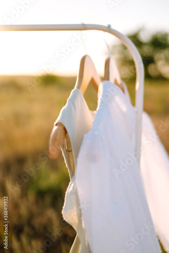 Summer dresses on a hanger at sunset. Summer, beauty, fashion, glamour, lifestyle concept.