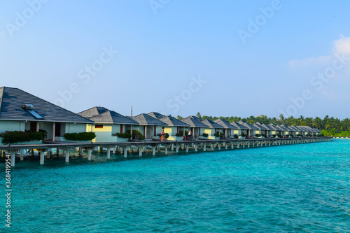 Sunny beach with white sand, coconut palm trees and turquoise sea. Summer vacation and tropical beach concept. Overwater at Maldive Island resort. © Matteo