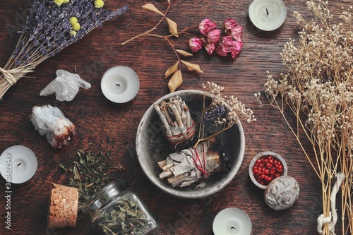 Sage smudge stick bundle in clay pot for burning on wiccan witch altar. Energy cleansing spell. Smoke cleansing air space room. Dried flowers, nature items, candles, crystals in the background