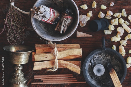 Flat lay various kinds of air element objects to use in witchcraft and wicca on witch's altar filled with sage smudge sticks, incense, Palo Santo tree, frankincense, charcoal disks for smoke cleansing