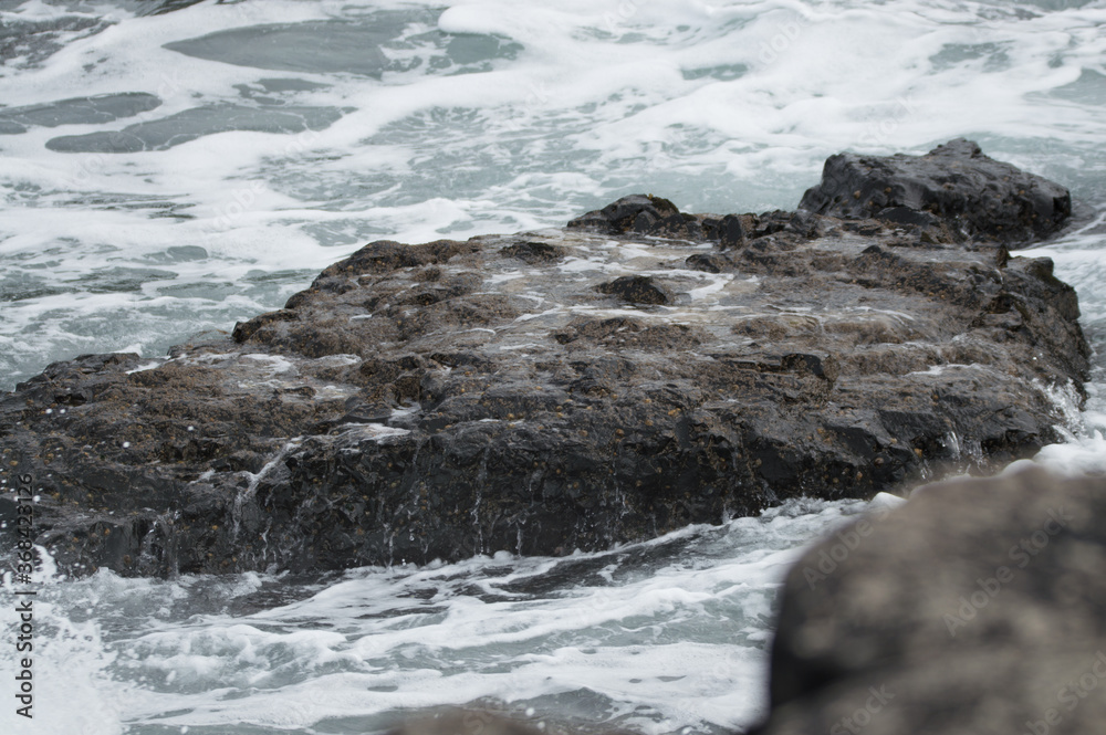 Naklejka premium Waves crashing against rocks at the Giant's Causeway, Northern Ireland.