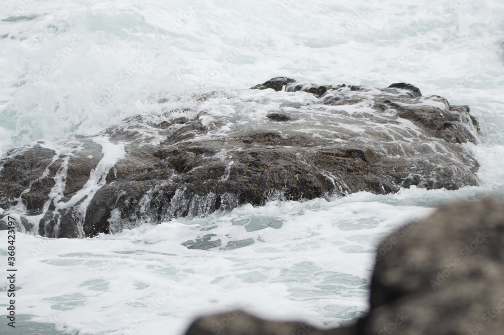 Waves crashing against rocks at the Giant's Causeway, Northern Ireland.