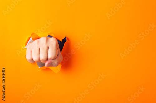 Foto Fist broke orange paper and torn a hole