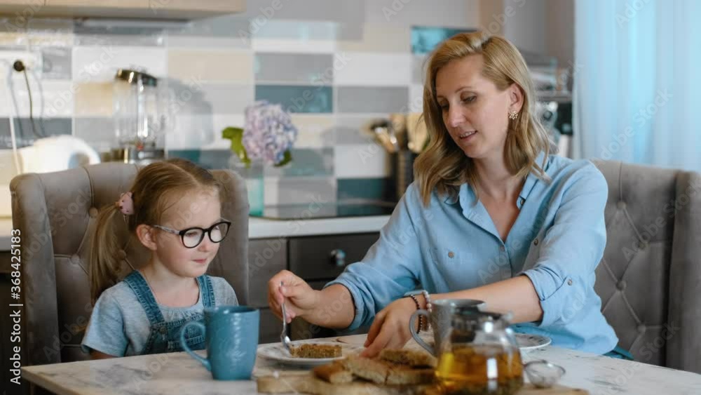 mom and daughter eat dessert food in kitchen Rbbro. mother and child have meal at the desk. feeding kid, sharing food tasting cake. preschool, togetherness, caucasian concept mom and daughter eat dessert food in kitchen Rbbro. mother and child have meal at the desk. feeding kid, sharing food tasting cake. preschool, togetherness, caucasian concept