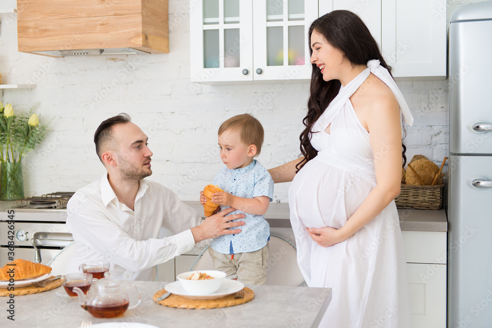 happy family in home kitchen married couple with a small child and pregnant woman happy family in home kitchen married couple with a small child and pregnant woman