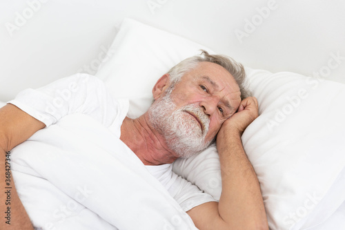Worried senior retirement man lying awake in his bed