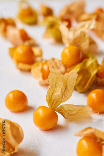 Cape gooseberry or Physalis on a white cloth background in angle, focusing onto one with the shell open.