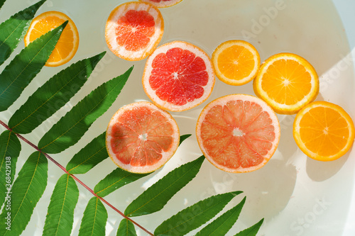 Orange  lemon  grapefruit fruits in the water with green leaves. Decoration for party  Citrus fruits in the bath at hot summer day. Fruits for cocktail